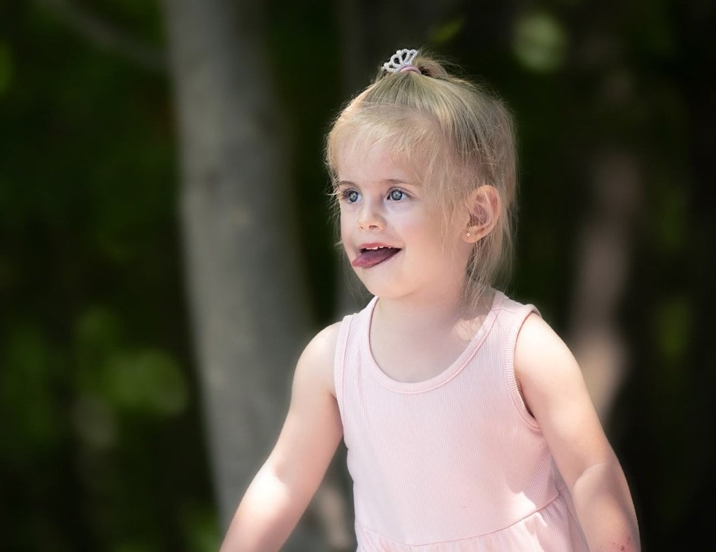 One of the twins outdoors in a pink dress