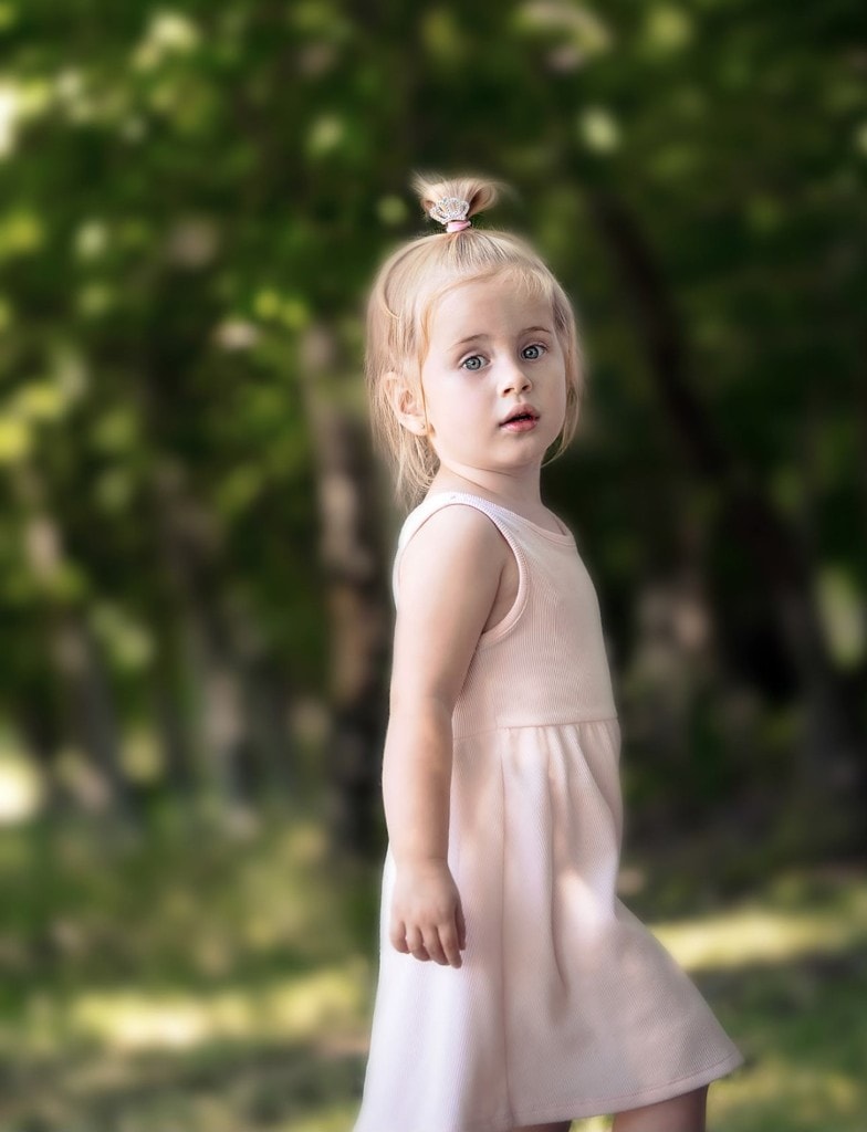 One of the twins in a pink dress standing outdoors