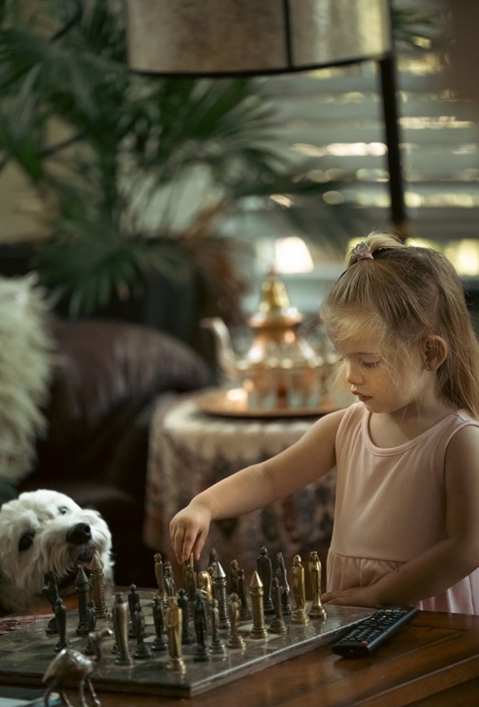 One of the twins playing chess at a styled table