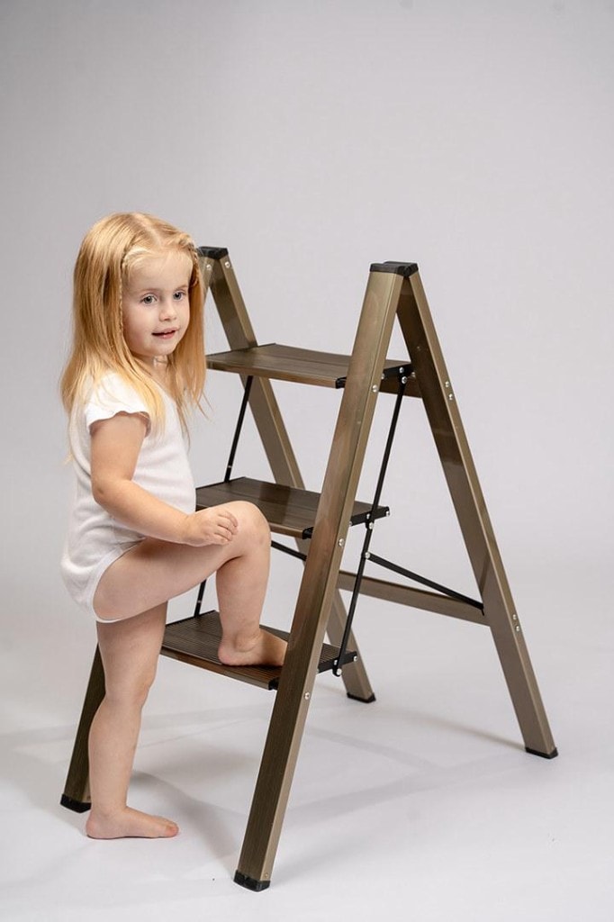 One of the twins sitting on a studio step ladder
