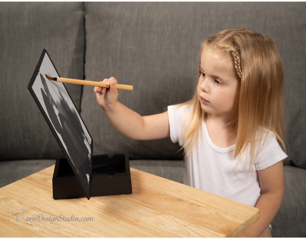 One of the twins painting at a wooden table